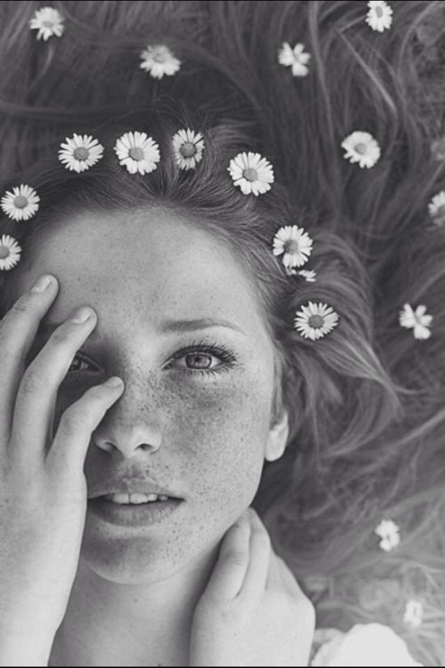 a woman with red hair and daisies on her head is looking at the camera