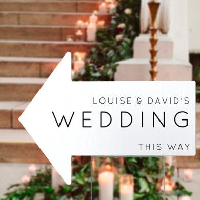 a sign that says louis and david's wedding this way with candles in the background