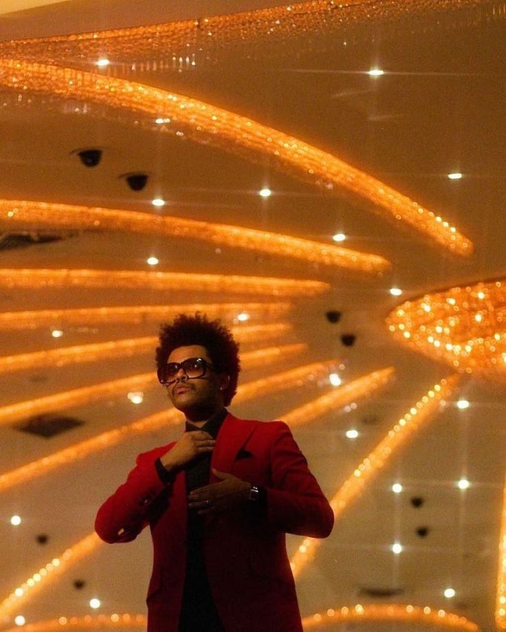 a man standing in front of a chandelier with lights hanging from the ceiling