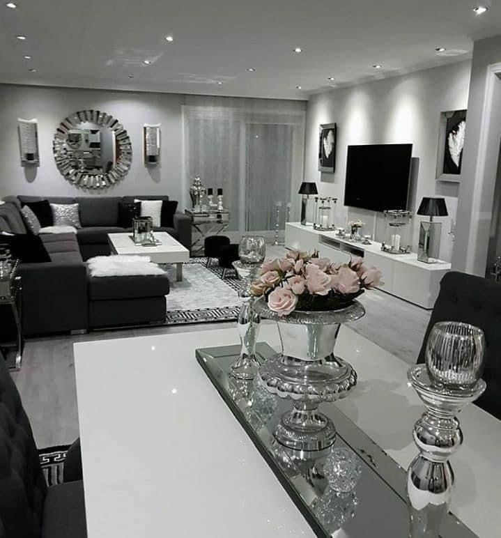 a living room filled with furniture and flowers on top of a glass table in front of a flat screen tv