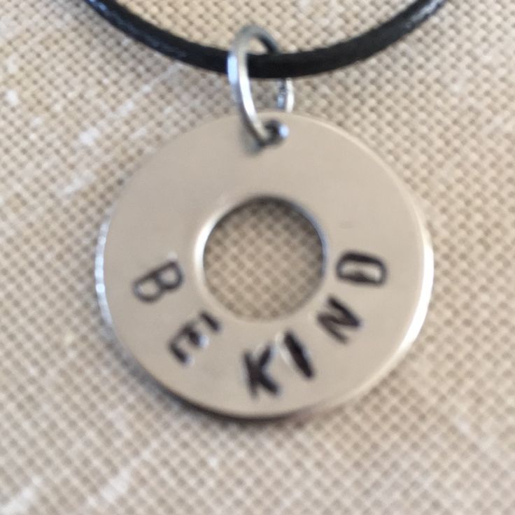 a necklace with the words be kind written on it and a circle in the middle