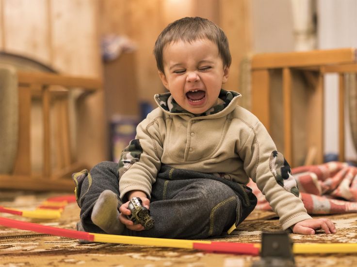 a young boy sitting on the floor with his mouth open