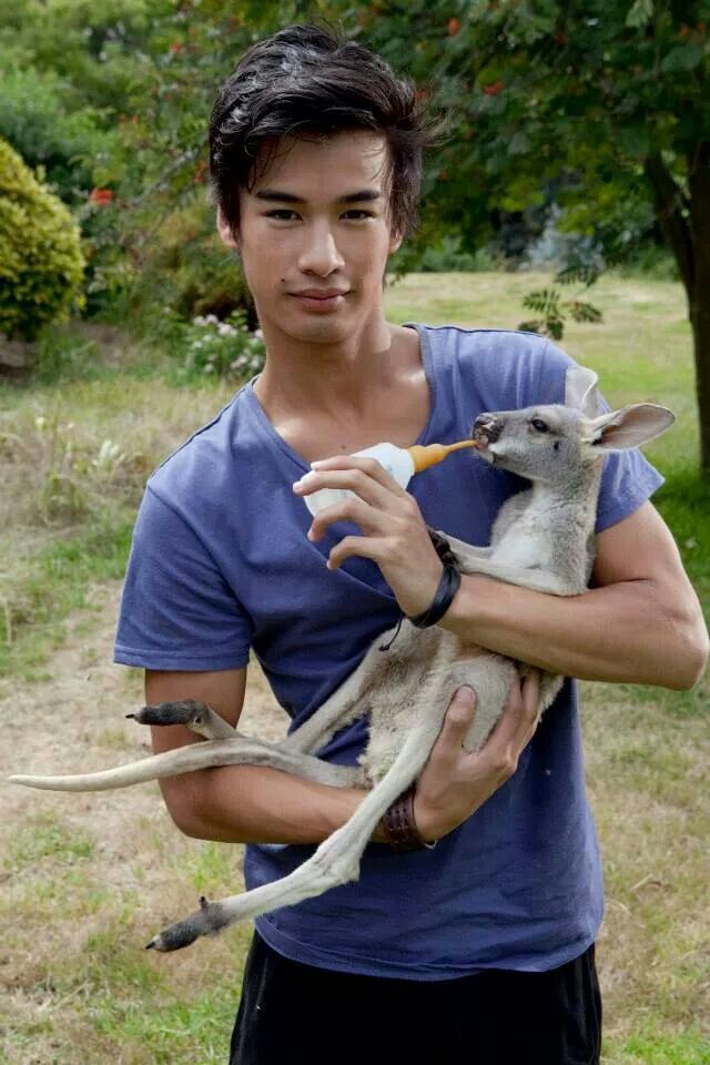 a young man holding a baby kangaroo in his arms with antlers on it's back