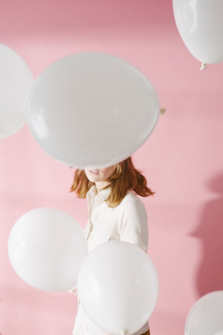 a woman holding balloons in front of her face