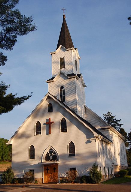 an old white church with a cross on the steeple