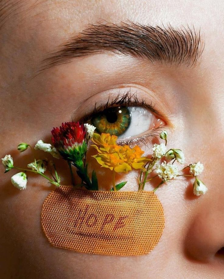 a woman with flowers on her eye and the word love spelled in front of her