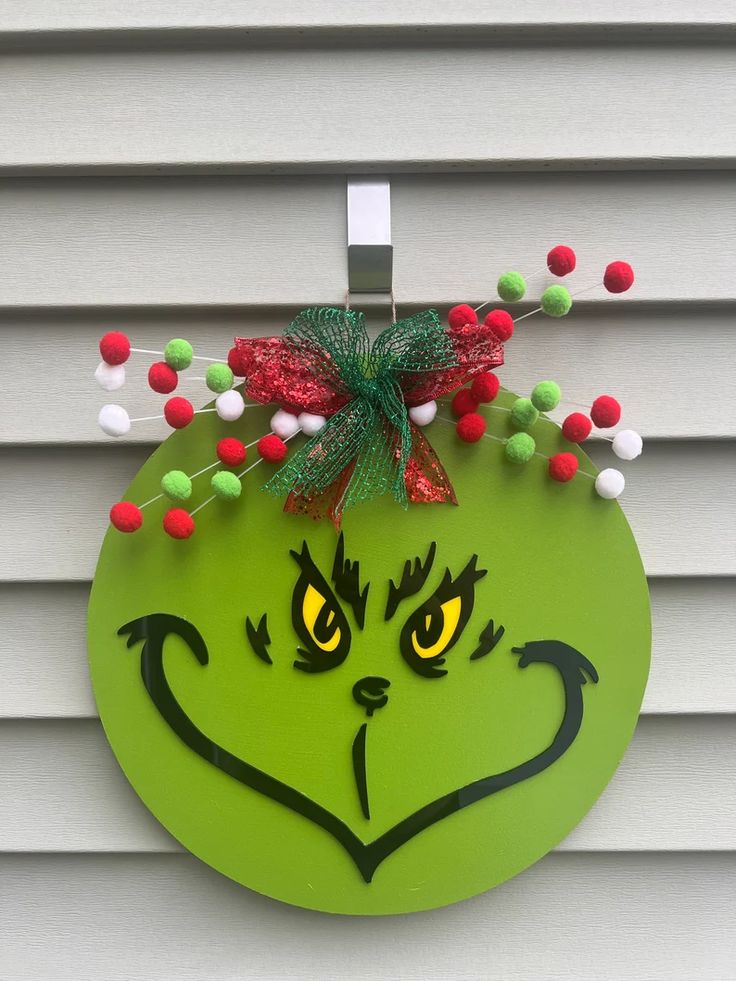 a green grin face hanging on the side of a house with red, white and green decorations