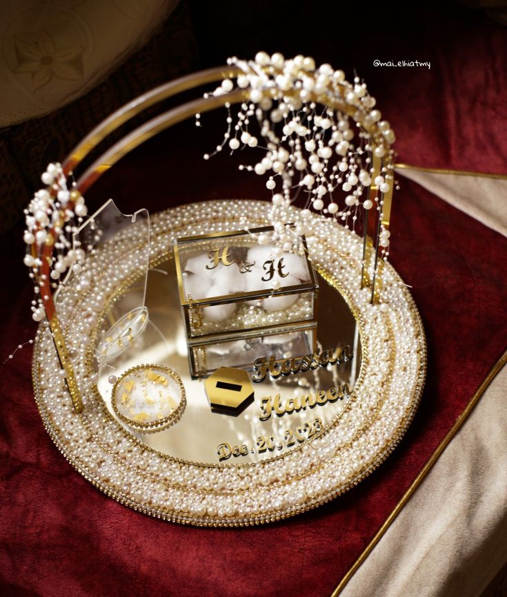 an elaborately decorated tray with pearls and beads on it is sitting on a red velvet surface