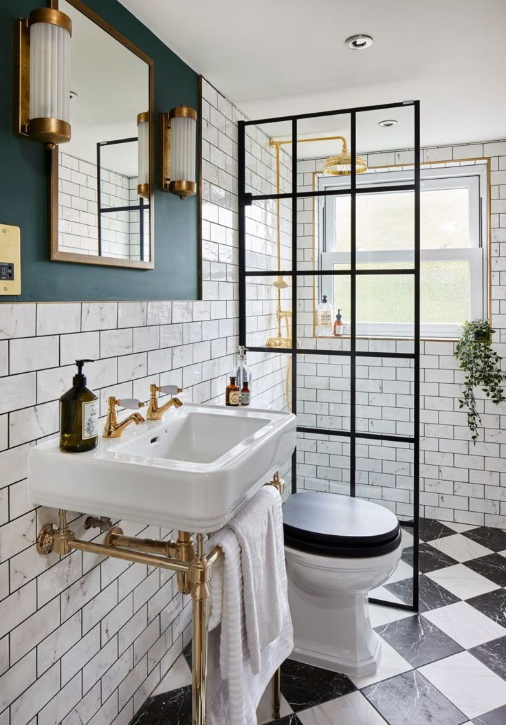 a bathroom with black and white checkered flooring, gold fixtures and mirrors on the wall