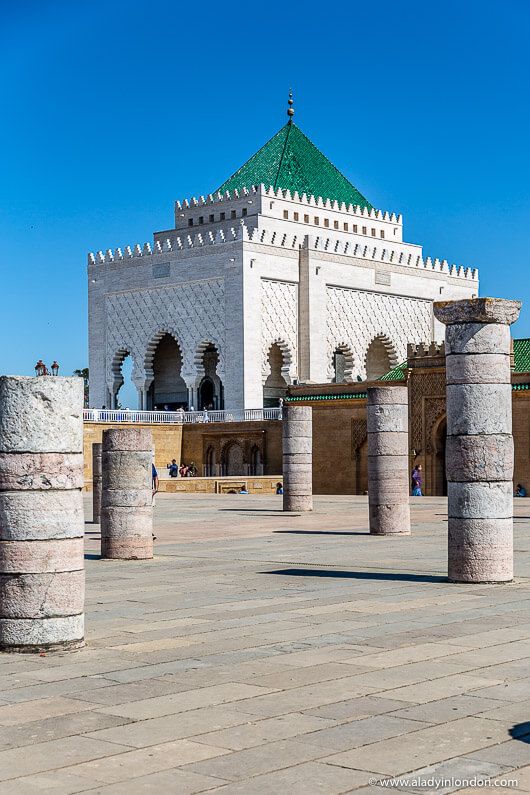 an old white building with columns and a green dome in the middle of it's courtyard