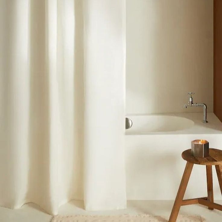 a white bath tub sitting next to a wooden stool