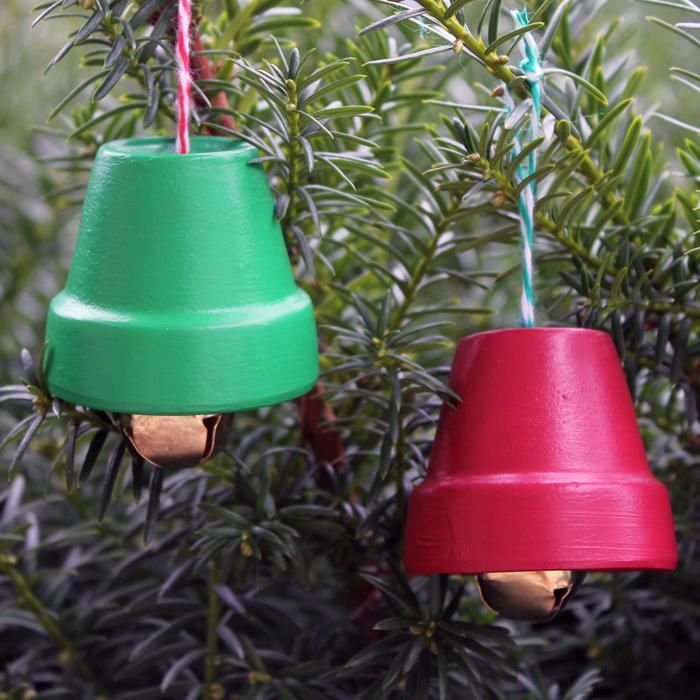 two colorful plastic bells hanging from a tree with green branches in the background and red, green, and blue cones attached to them