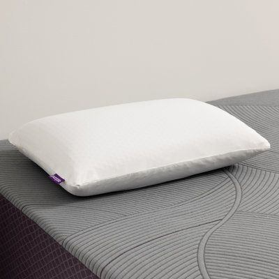 a white pillow sitting on top of a bed next to a gray and purple mattress