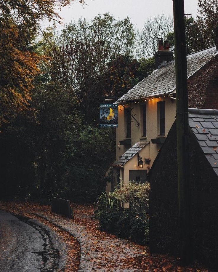 a white house sitting on the side of a road next to a tree filled forest