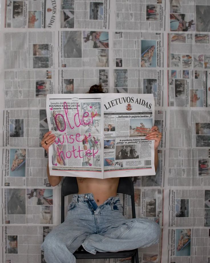 a person sitting in a chair reading a newspaper