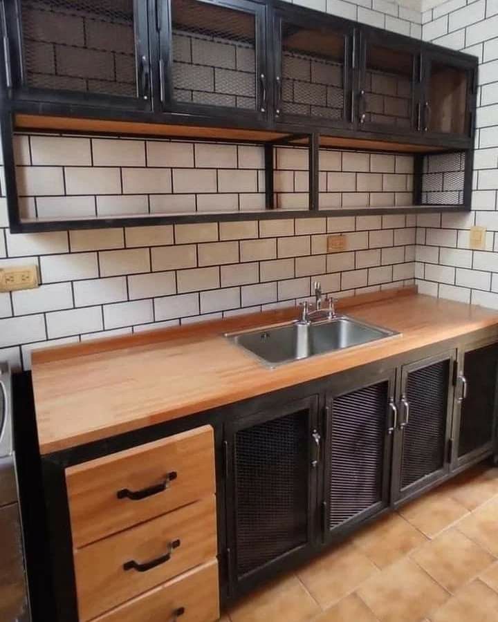 an empty kitchen with black cabinets and wooden counter tops in front of a white tiled wall