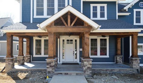 a blue house with white trim and stone pillars on the front porch is under construction