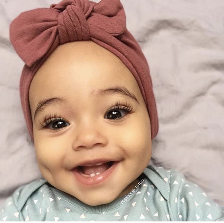 a smiling baby with a pink bow on her head