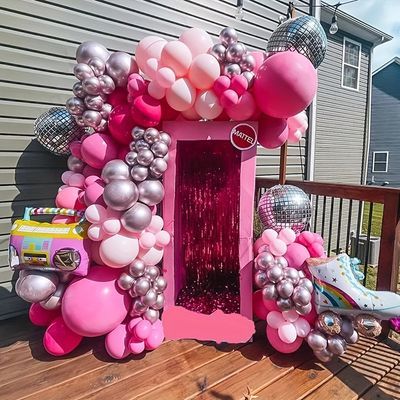 a barbie doll house made out of balloons and other items on a wooden deck with a building in the background