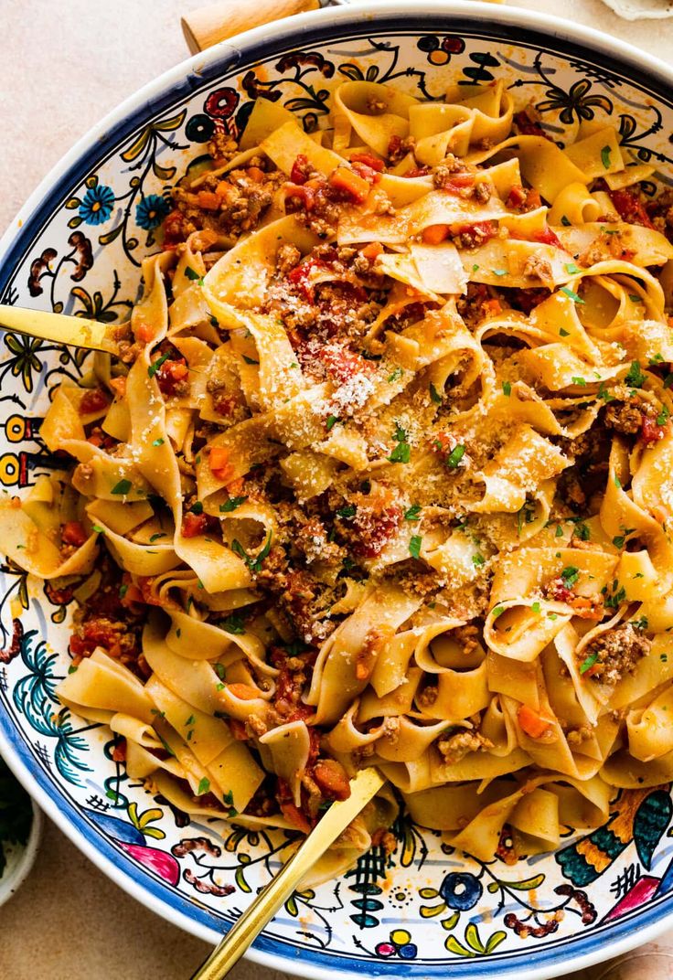 a bowl filled with pasta and meat on top of a table next to a fork