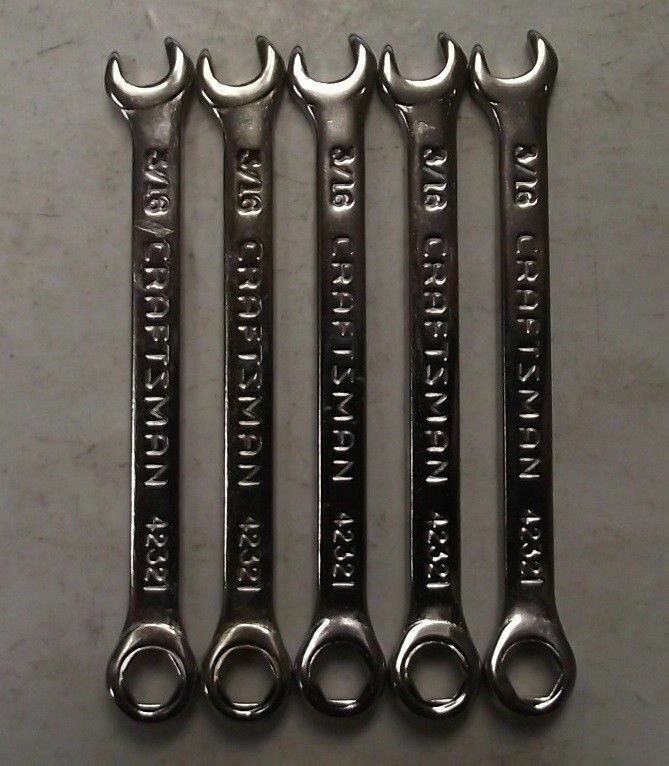 four wrenches are sitting side by side on a table