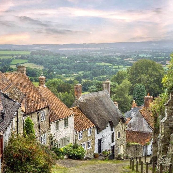 an old village with stone buildings and green fields in the background