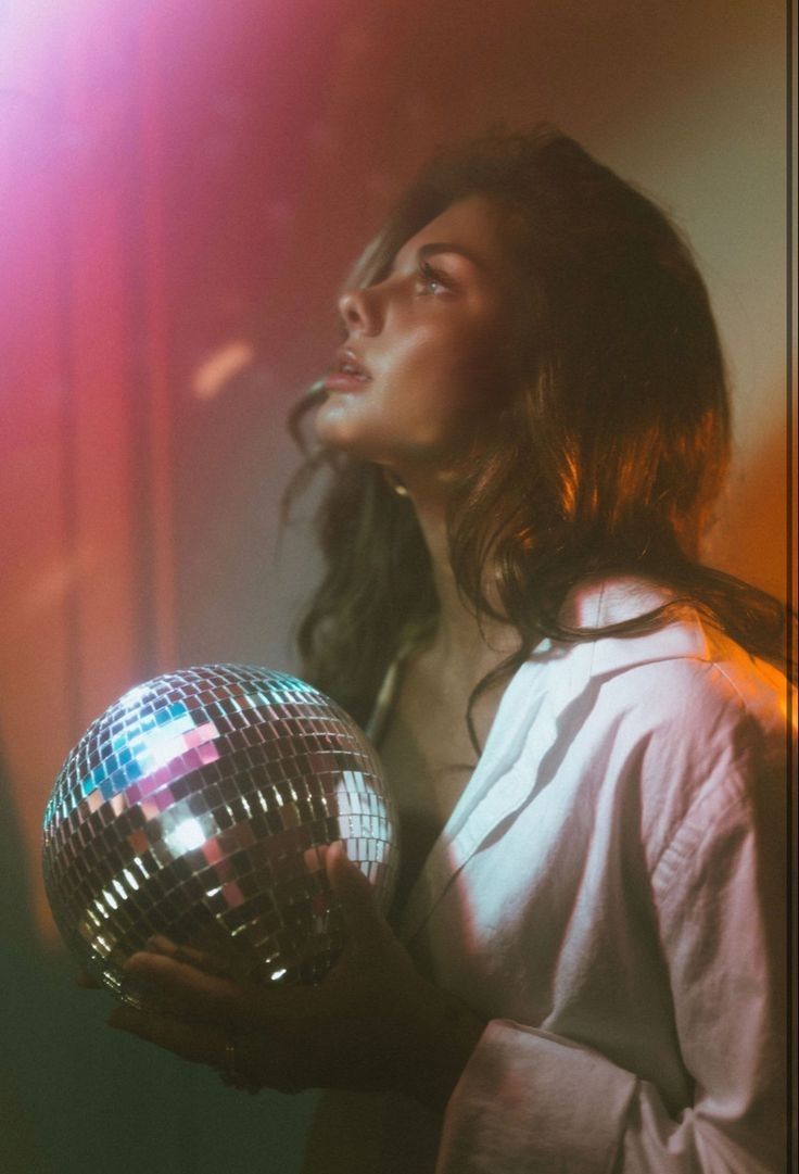 a woman holding a disco ball in her hands