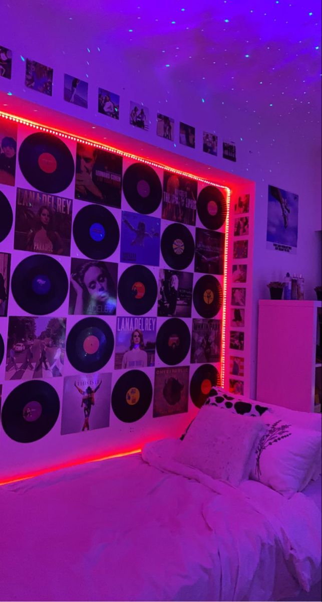 a bed with lots of records on the wall and lights in the room above it