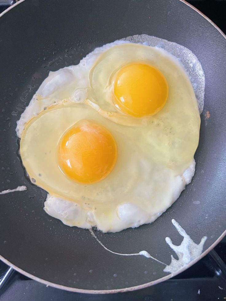 two fried eggs in a frying pan on the stove