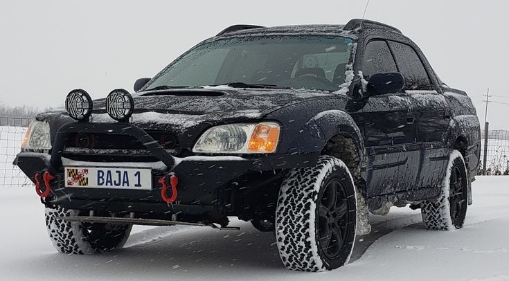 a black truck parked in the snow with its lights turned on and it's front bumper up