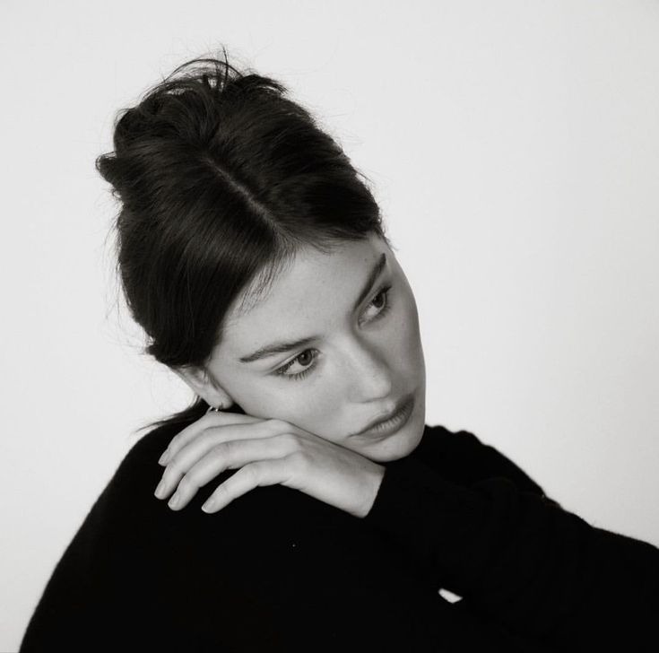 a black and white photo of a woman with her hand on her shoulder