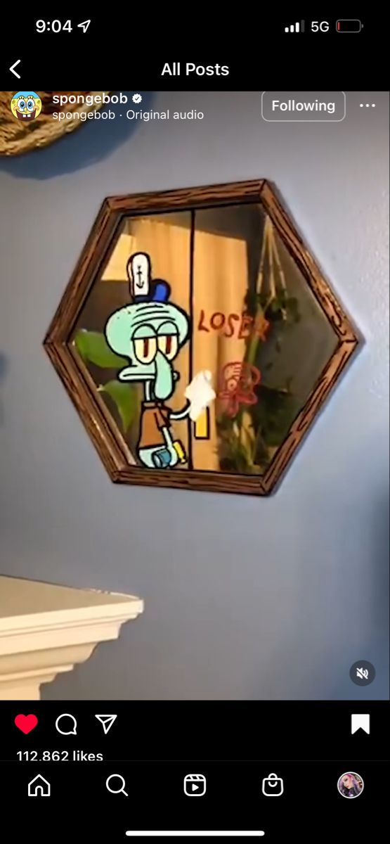 a clock hanging on the side of a blue wall next to a window with an image of a cartoon character