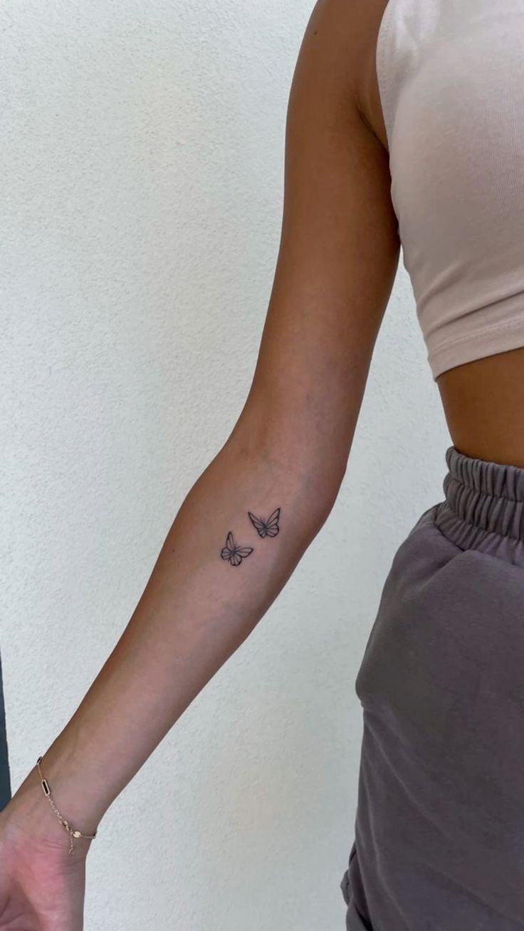 a woman's arm with a butterfly tattoo on the left side of her arm