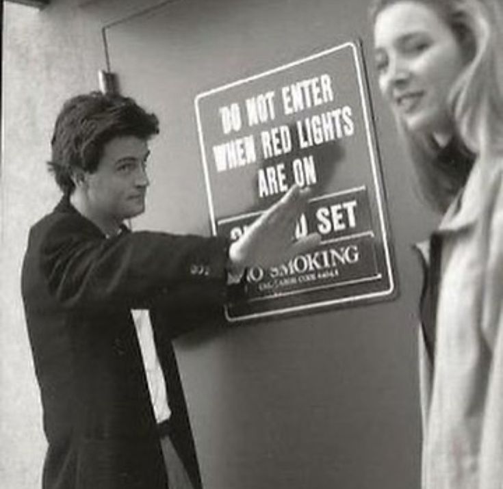 a man and woman standing next to a sign