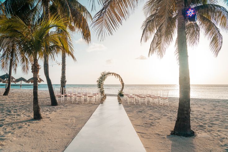 an outdoor ceremony setup on the beach with palm trees