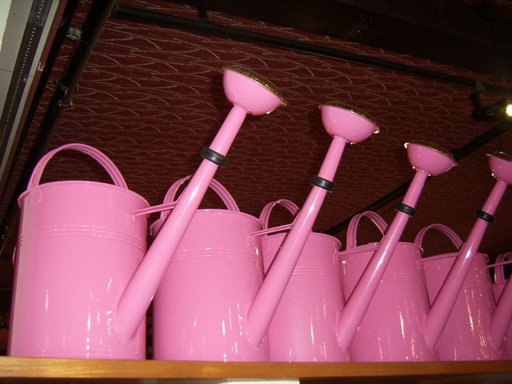 many pink buckets and shovels are lined up in a row on the shelf