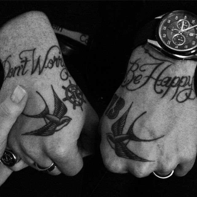 two people with tattoos on their hands holding each other's hand and the words don't worry, be happy