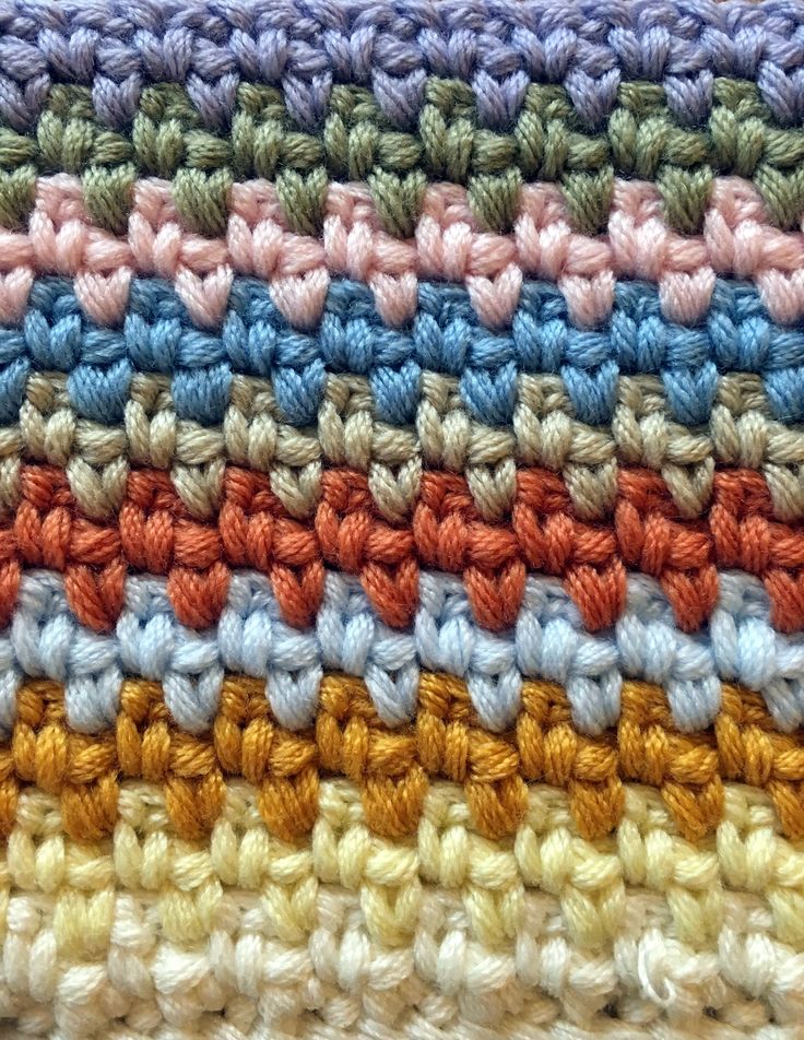 a multicolored crocheted dishcloth on a wooden surface