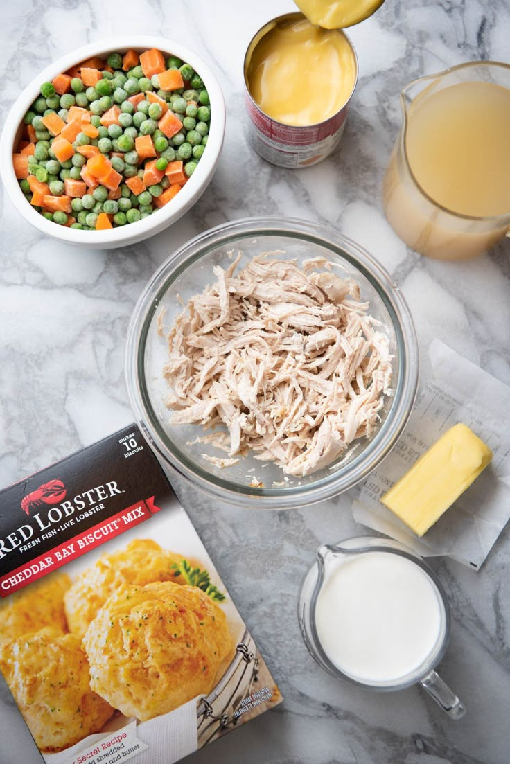 ingredients to make chicken pot pie laid out on a marble counter top with milk, eggs, butter, and other foodstuffs