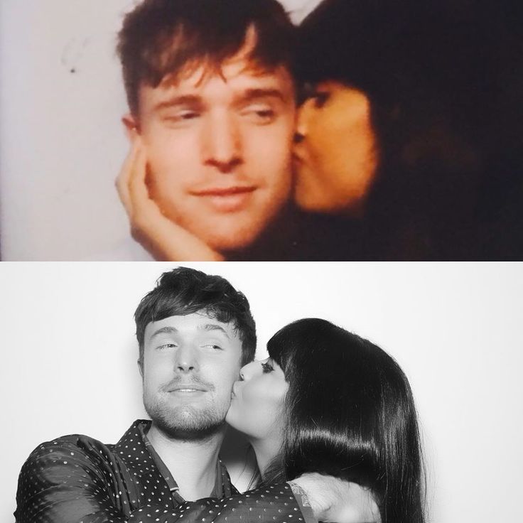 a man and woman kissing each other in front of a white wall with two pictures behind them