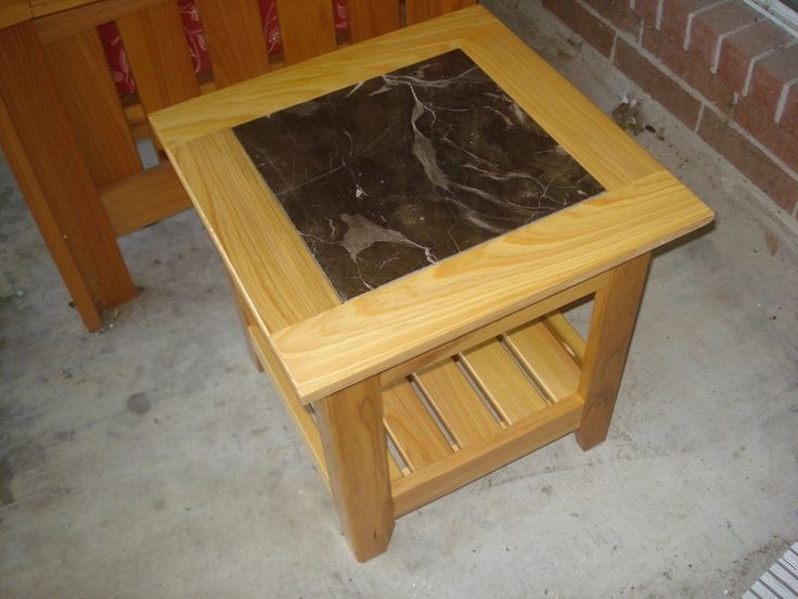 a small wooden table sitting next to a brick wall