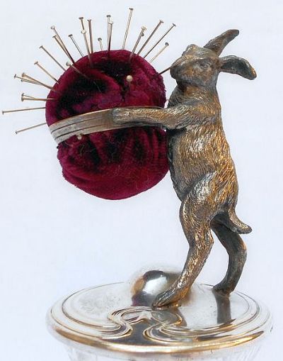 a metal dog figurine holding a ball of thread