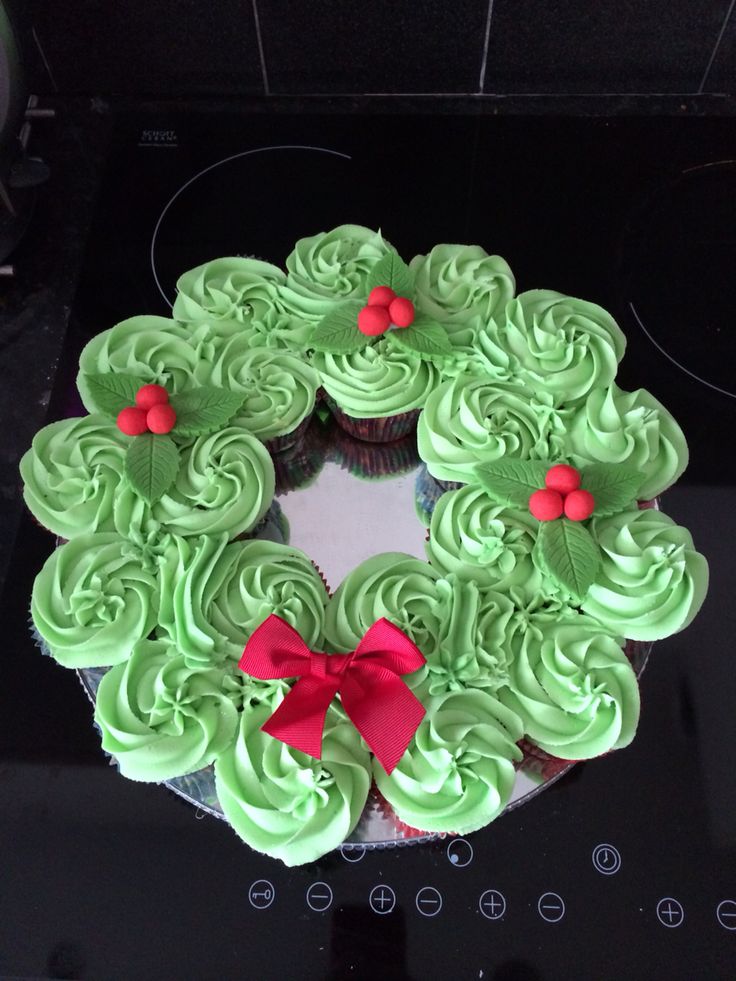 cupcakes with green frosting and red bows are arranged in a wreath on top of the stove