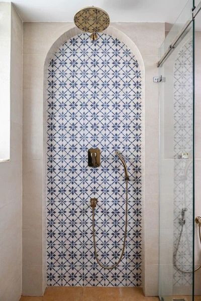 a bathroom with blue and white tiles on the wall, shower head, and glass door