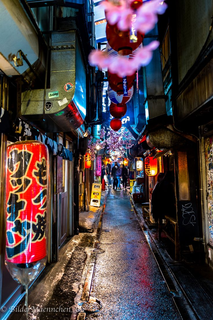 an alley way with people walking down it and lanterns hanging from the ceiling above them