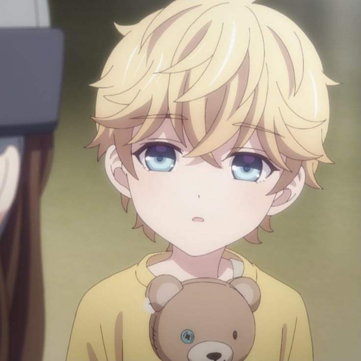 a boy with blonde hair and blue eyes holding a teddy bear in front of him