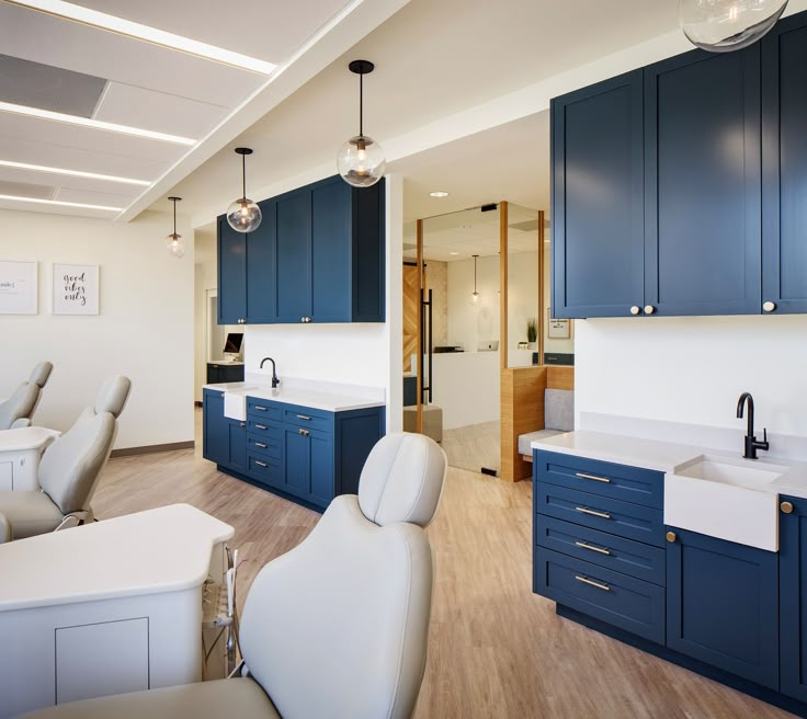 an open kitchen with blue cabinets and white counter tops, along with modern style chairs