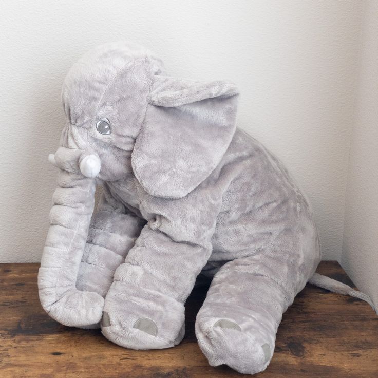 an elephant stuffed animal sitting on top of a wooden table next to a white wall