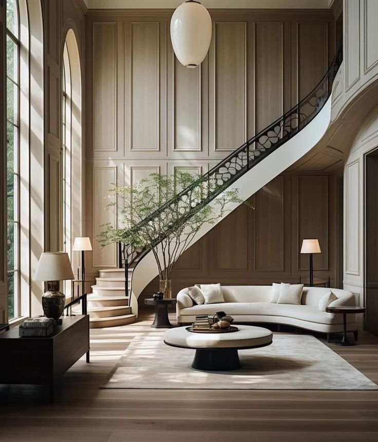 an elegant living room with white furniture and wood paneled walls, along with a spiral staircase leading up to the second floor