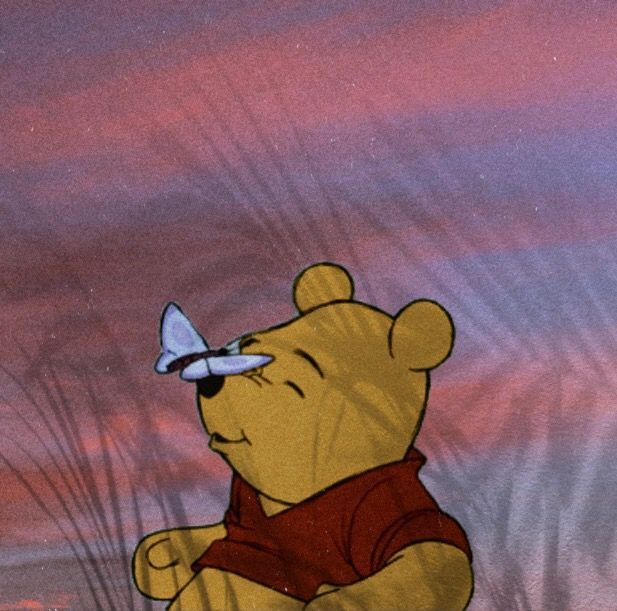 a winnie the pooh character with a butterfly on his nose and in front of a pink sky